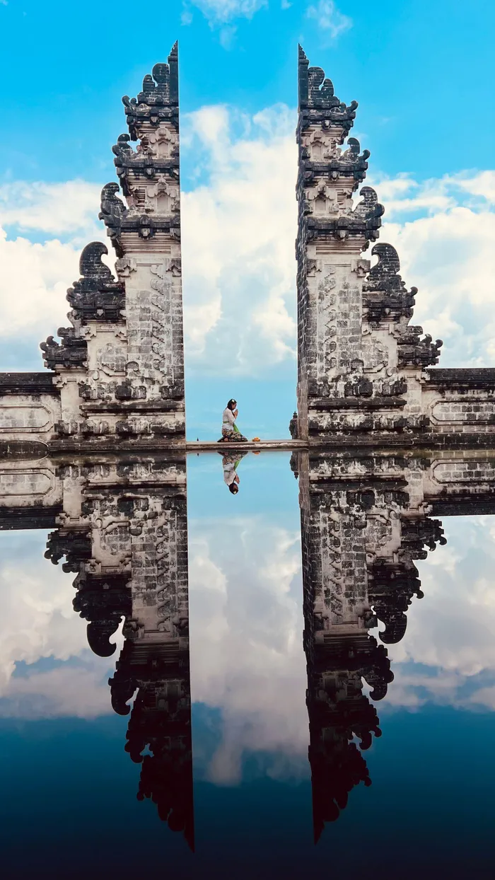 In Bali, Indonesia, the split gate of Pura Lempuyang displays a striking reflective symmetry against a brilliant blue sky.
