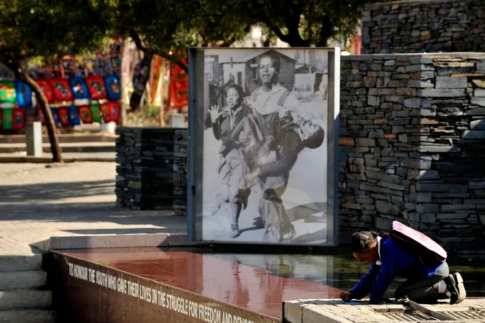 A little girl plays next to the 1976 picture at the Hector Peterson Memorial in Soweto. 50 years since the uprising, learners continue to face challenges, including water shortages and loadshedding.
