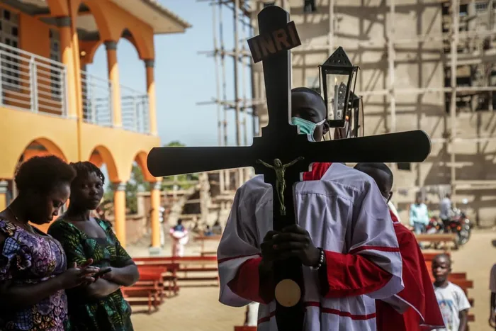 An altar server carries a cross while wearing a mask following local authorities’ instructions to limit the spread of the Ebola outbreak in eastern Democratic Republic of the Congo during a mass at Bunia Cathedral in Bunia. 